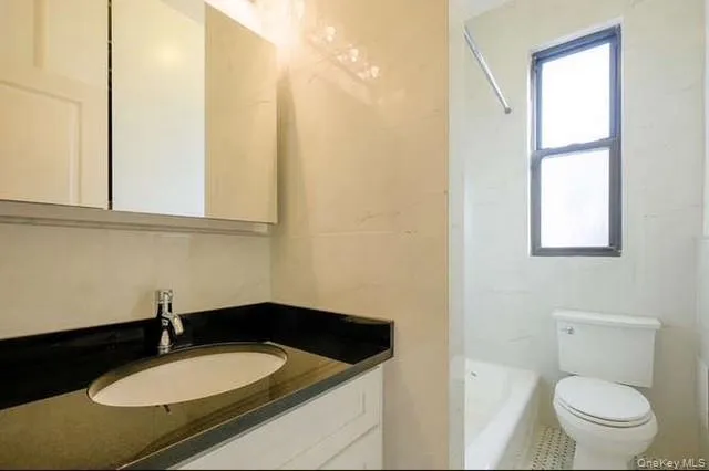 a bathroom with a granite countertop sink toilet and a mirror