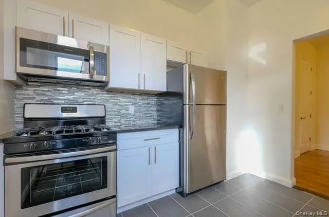 a kitchen with stainless steel appliances granite countertop a stove microwave and refrigerator