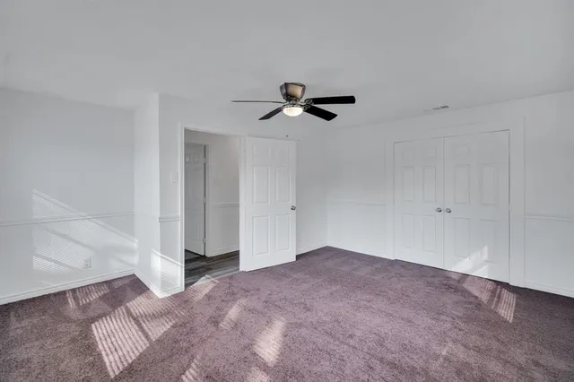 a view of an empty room with a ceiling fan and window