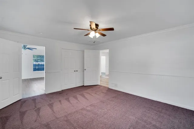 an empty room with closet and a ceiling fan