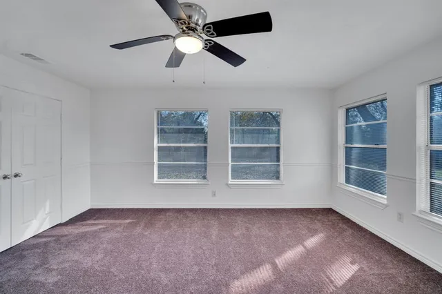 an empty room with windows and ceiling fan