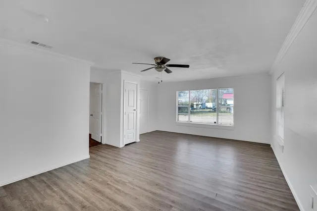 a view of an empty room with wooden floor and a window