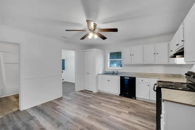 a kitchen with granite countertop a stove cabinets and wooden floor
