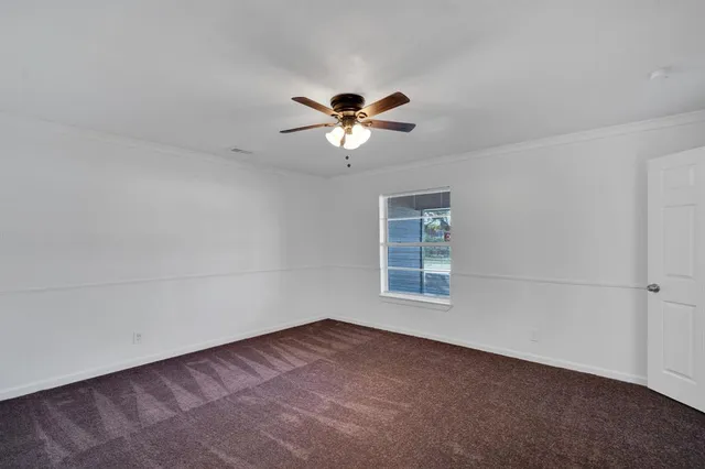 an empty room with windows and chandelier fan