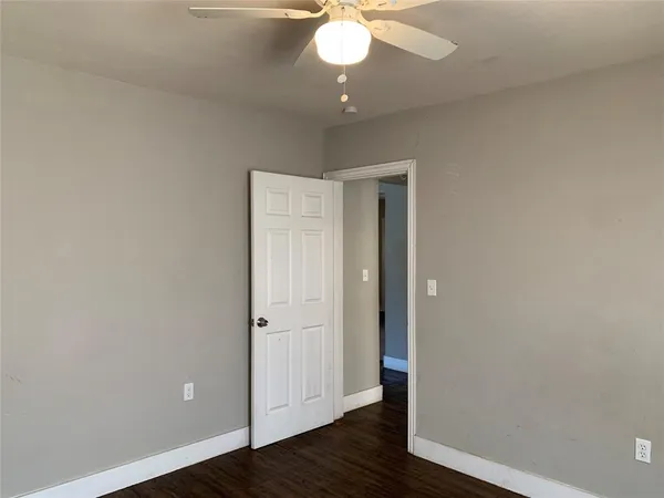 an empty room with wooden floor and a ceiling fan