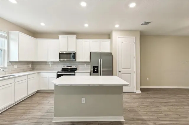 a kitchen with stainless steel appliances granite countertop a refrigerator stove top oven and sink