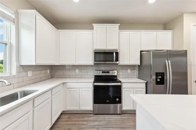 a kitchen with white cabinets and stainless steel appliances