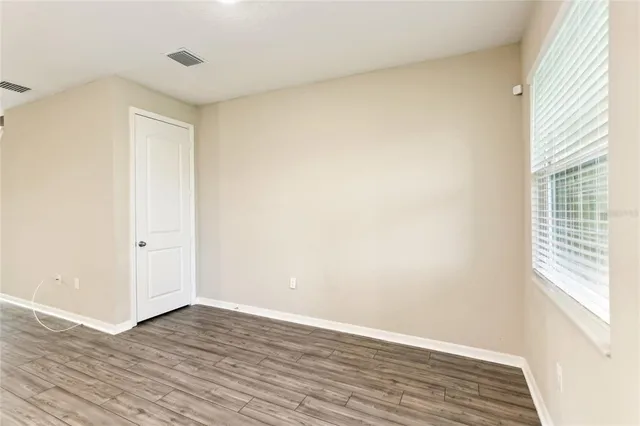 a view of an empty room with wooden floor and a window