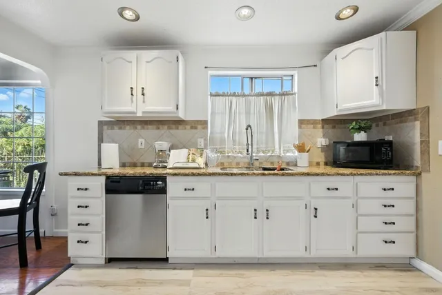 a kitchen with white cabinets and sink