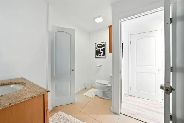 a bathroom with a granite countertop sink a toilet a shower and a mirror