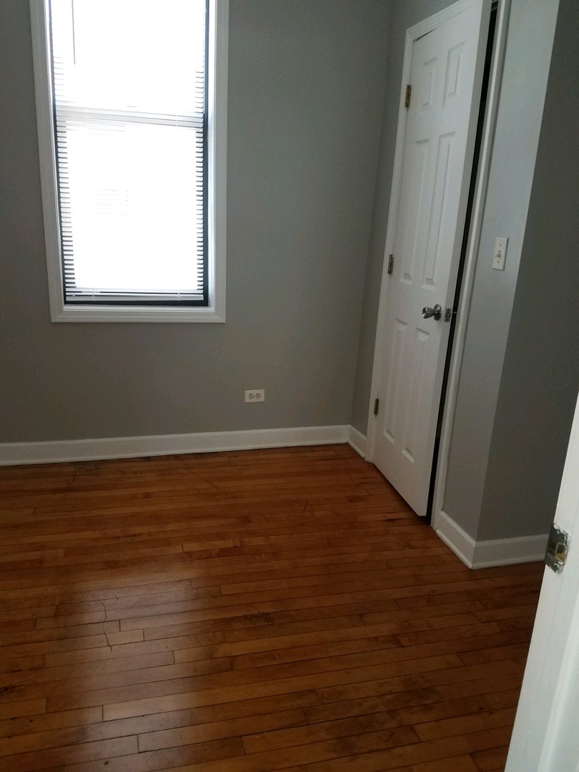 1640 South Springfield Avenue Chicago, IL 60623 - Photo 7 of 11 an empty room with wooden floor and a window