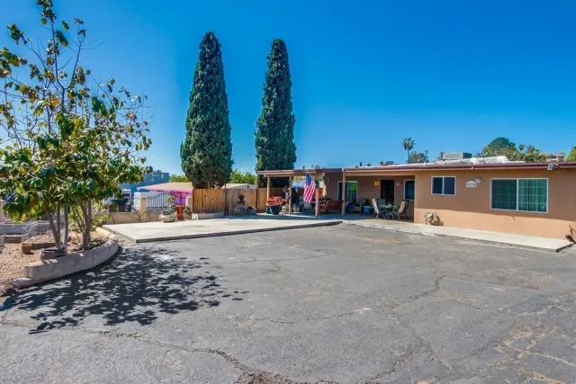a view of a white house with a big yard and large trees