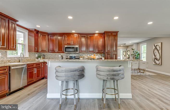 4105 30th Street Mount Rainier, MD 20712 - Photo 18 of 98 a kitchen with stainless steel appliances granite countertop a stove a sink a refrigerator a dining table and chairs with wooden floor