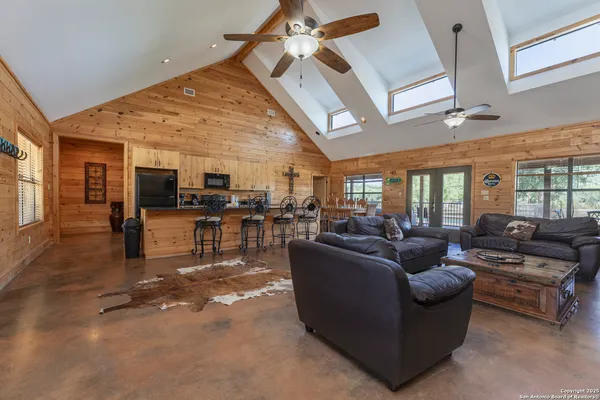 a living room with furniture kitchen view and a large window