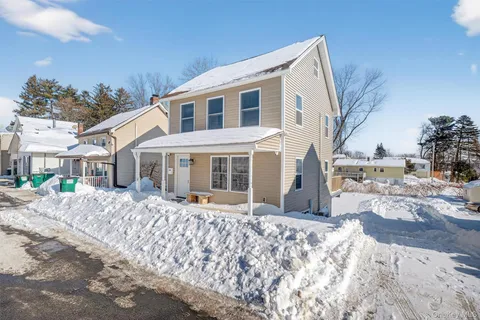 a front view of a house with a yard covered with snow
