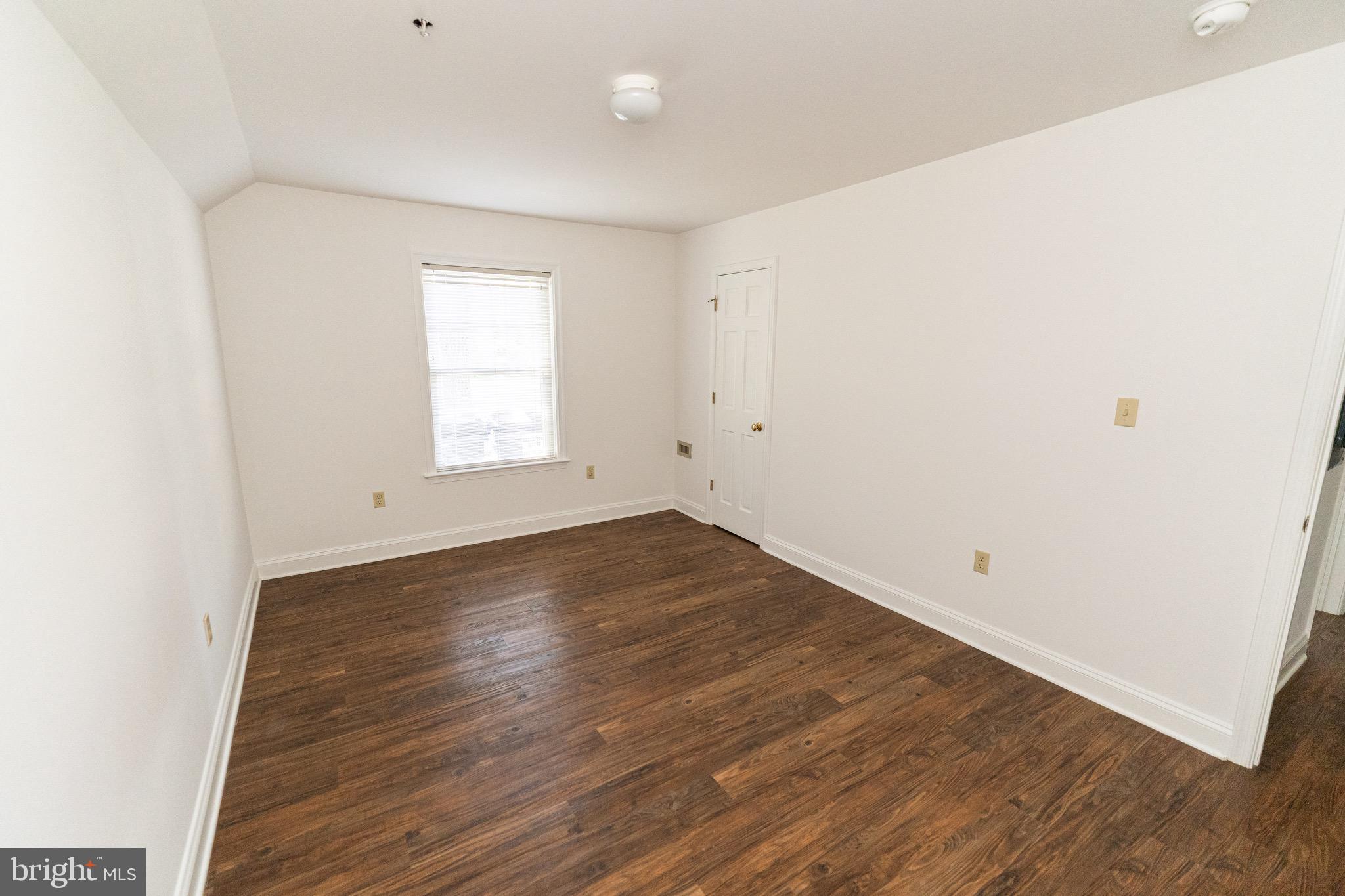 804 Travers Street, Unit 2 Cambridge, MD 21613 - Photo 17 of 26 an empty room with wooden floor and window