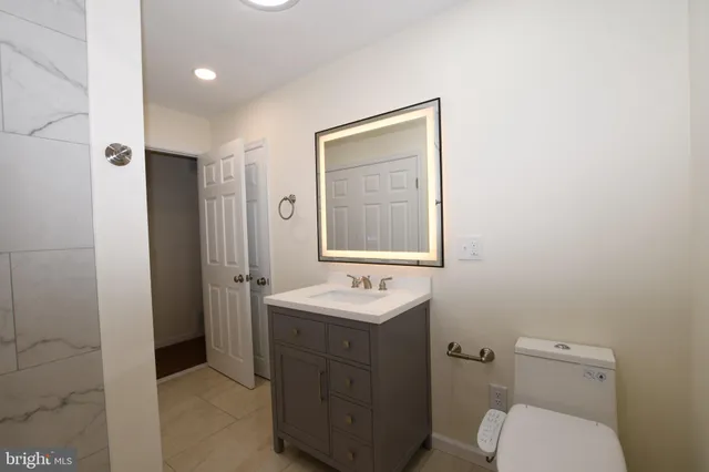 a bathroom with a toilet sink vanity and mirror
