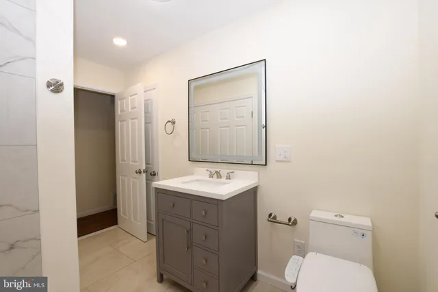 a bathroom with a toilet sink vanity and mirror