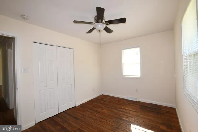 a view of empty room with wooden floor and fan