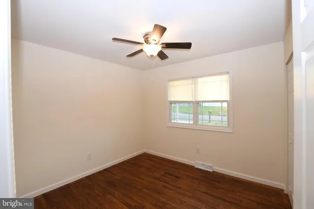 an empty room with wooden floor fan and windows