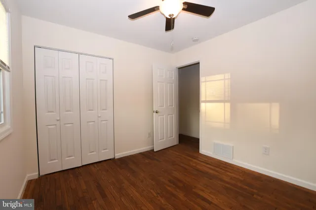 an empty room with wooden floor cabinet and windows