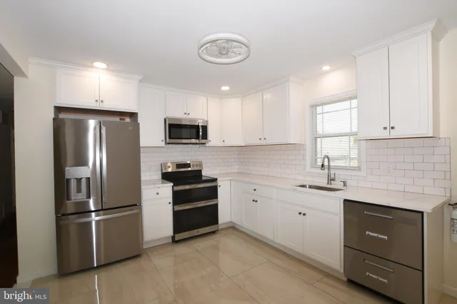 a kitchen with granite countertop a refrigerator stove and sink