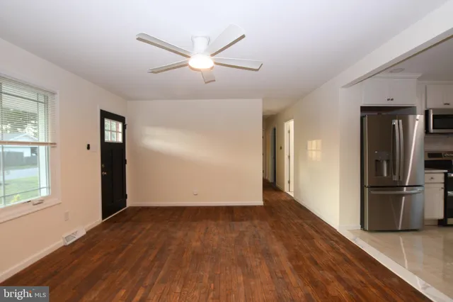 an empty room with wooden floor a ceiling fan and windows