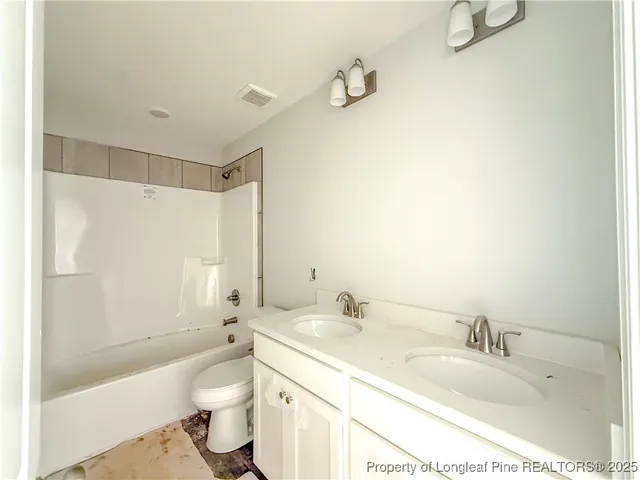 a bathroom with a granite countertop sink a toilet and shower