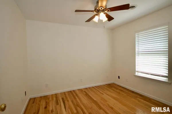 an empty room with a window and a fan