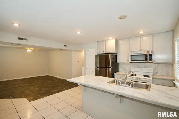 a kitchen with stainless steel appliances a sink a stove a microwave a refrigerator a counter top space and cabinets