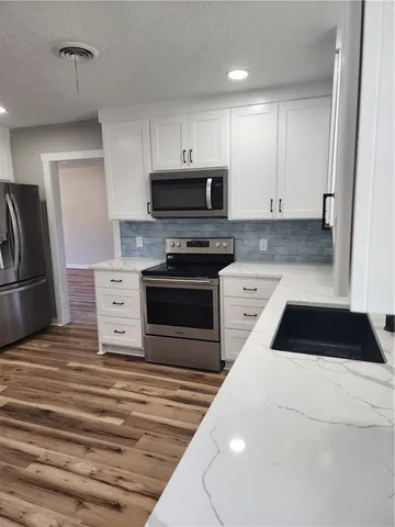 a kitchen with granite countertop a refrigerator stove and cabinets