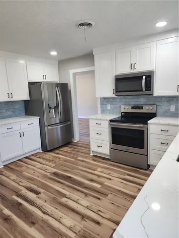 a kitchen with stainless steel appliances granite countertop a stove a refrigerator and a microwave oven