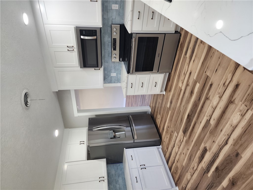 12877 East State Highway 21 Bryan, TX 77808 - Photo 12 of 48 a kitchen with stainless steel appliances granite countertop a stove a refrigerator and a microwave oven