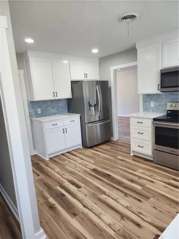 a kitchen with stainless steel appliances kitchen island wooden cabinets and fireplace