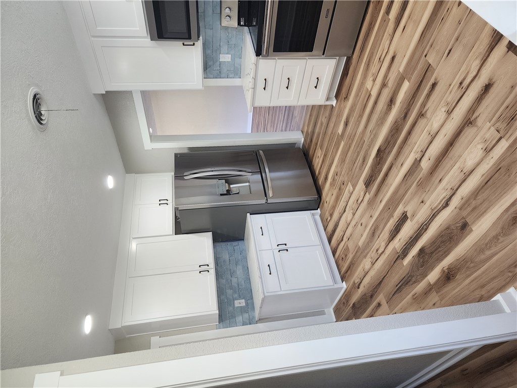 12877 East State Highway 21 Bryan, TX 77808 - Photo 13 of 48 a kitchen with stainless steel appliances kitchen island wooden cabinets and fireplace