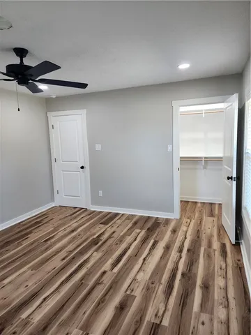 a view of a room with a ceiling fan and wooden floor