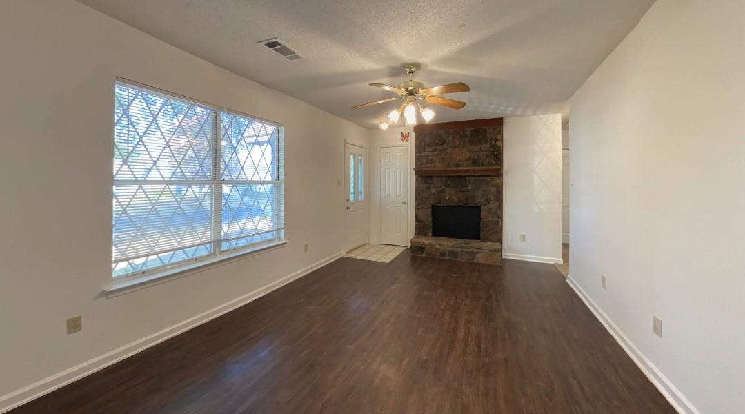 6659 Elmore Ridge Lane Memphis, TN 38134 - Photo 5 of 8 Unfurnished living room with ceiling fan, a fireplace, a textured ceiling, and dark hardwood / wood-style floors