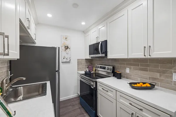 a kitchen with stainless steel appliances granite countertop a refrigerator a stove a microwave oven a sink and dishwasher with wooden floor