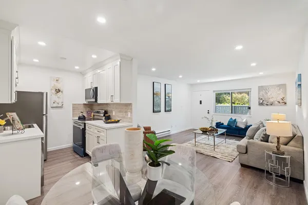 a living room with furniture kitchen area and a large window