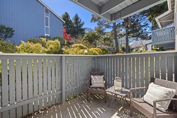 a view of a chairs and table in the back yard of the house and wooden fence