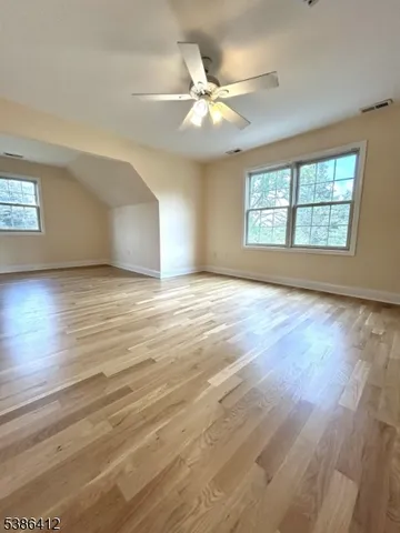 an empty room with wooden floor fan and windows