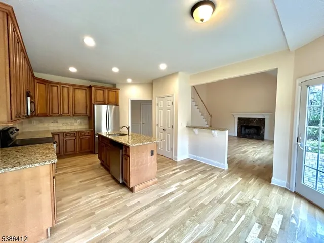 a large kitchen with stainless steel appliances kitchen island granite countertop a stove a sink and a granite countertops with wooden floor