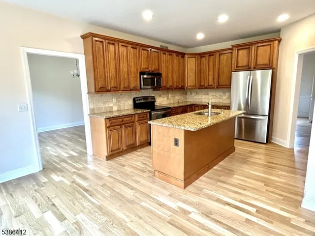 a kitchen with stainless steel appliances granite countertop a stove top oven a sink and a refrigerator