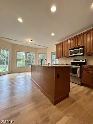 a kitchen with stainless steel appliances granite countertop a stove top oven a sink dishwasher a refrigerator and cabinets with wooden floor