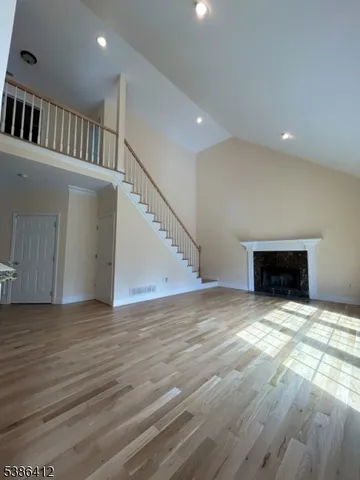 a view of an empty room with wooden floor and a fireplace