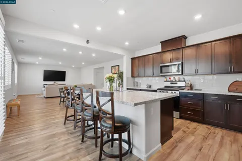 a large kitchen with stainless steel appliances granite countertop a lot of counter space and wooden floor