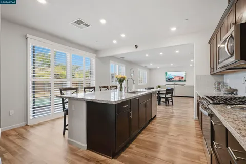 a kitchen with kitchen island granite countertop a sink a counter space cabinets and stainless steel appliances