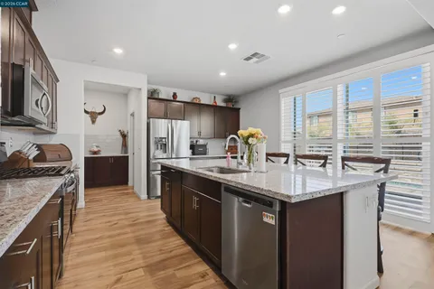 a kitchen with stainless steel appliances wooden cabinets granite counter tops a stove a sink and a refrigerator