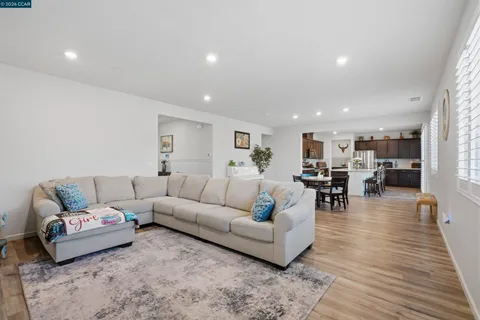 a living room with furniture and kitchen view with wooden floor