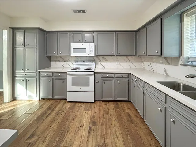 a kitchen with stainless steel appliances granite countertop a sink cabinets and wooden floor